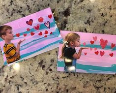 two children's valentine cards with hearts painted on them, sitting on a marble countertop