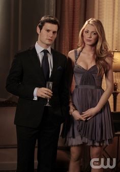 a man and woman standing next to each other in front of a table with wine glasses