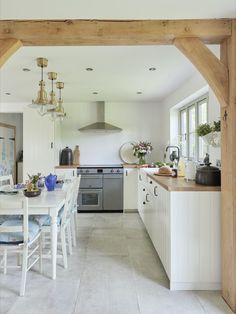 an open kitchen and dining room area with white cabinets, wood beams, and blue accents