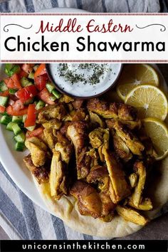 chicken shawarma on a plate with lemons, tomatoes and cucumbers