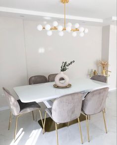 a dining room table with chairs and a vase on it in front of a white wall