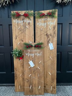 two wooden boards decorated with christmas decorations and writing on them, sitting in front of a black door