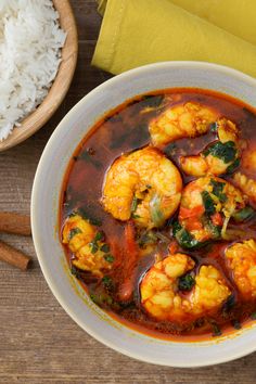 a white bowl filled with shrimp and vegetables next to rice