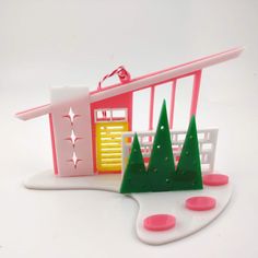 New** Mid Century Modern Putz House Style, Retro 'Shed or Slant Roof' House Ornament   Colors: Choose one of 8 beautiful Acrylic colors. The house sits on a White Acrylic Boomerang shaped base except the Bright White that sits on a Black Acrylic Boomerang base.  Each house comes complete with Christmas Trees, Steppingstones and some with Breeze Blocks.  Door colors may vary at artist discretion. Size: 2.25" H x 4.5" W x 2.75" D Collect all 6 Putz House Styles in each of their 8 colors here: Ranch - https://www.etsy.com/listing/1499315840 Butterfly Roof - https://www.etsy.com/listing/1513492819 RicRac Roof - https://www.etsy.com/listing/1513488469 Split Level - https://www.etsy.com/listing/1499314504 A-Frame - https://www.etsy.com/listing/1499320194 Shed Roof - https://www.etsy.com/listing/ Mid Century Modern Xmas Tree, Funky Christmas Trees Mid Century, Anthropologie Christmas Tree Mid Century, Mid Century Modern Christmas Fireplace, Anthropologie Christmas Mid Century, Black And White Xmas Tree Mid Century, Mid Century Christmas Tree Ornament, Mid Century Ornaments, Mid Century Modern Christmas Decorations