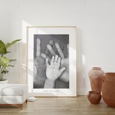 a black and white photo of two hands in front of a potted plant on a table