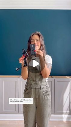 a woman taking a selfie in front of a blue wall with her cell phone