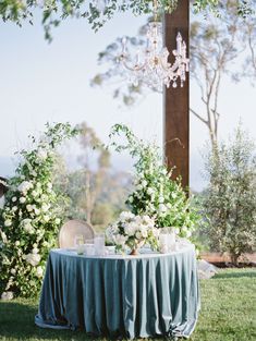 the table is set with flowers and greenery on it for an outdoor wedding reception