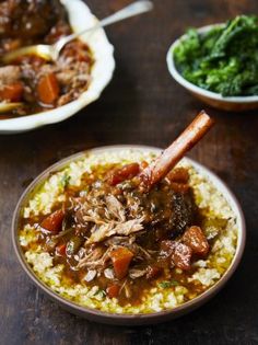 two bowls filled with food on top of a wooden table next to green vegetables and meat