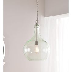 a glass light fixture hanging from a ceiling in a room with white walls and curtains