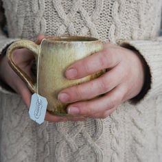 a close up of a person holding a coffee cup with a tag in their hand