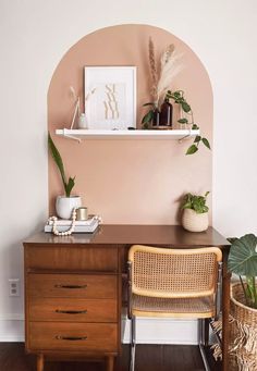 a wooden desk topped with a brown chair next to a shelf filled with potted plants