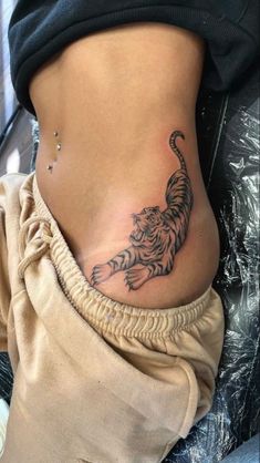 a woman's stomach with a tiger tattoo on her lower back and the side