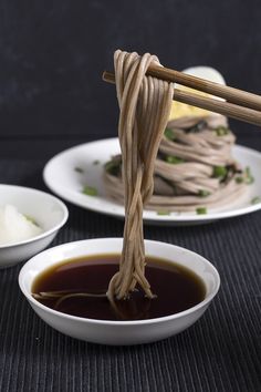 chopsticks are being used to stir food in small white bowls on a table