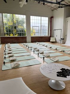 rows of yoga mats are arranged on the floor in an empty room with large windows