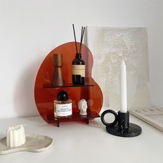 a shelf with candles, bottles and other items on it next to a candle holder