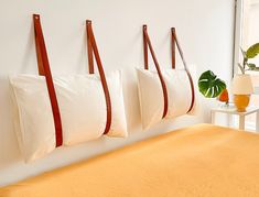 three pillows hanging on the wall above a bed