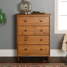 a wooden dresser sitting next to a window in a room with a rug on the floor