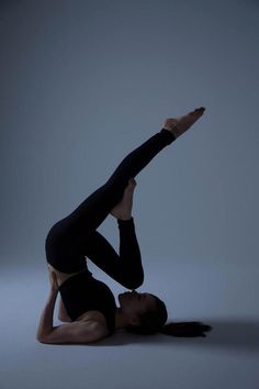 a woman in black leotard doing a handstand on the floor with her legs crossed