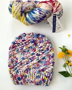 two skeins of yarn sitting next to each other on a white surface with flowers