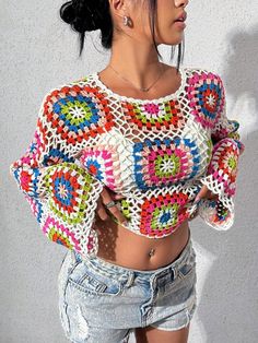 a woman wearing shorts and a crochet top is standing in front of a wall