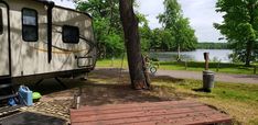 an rv parked next to a tree near the water