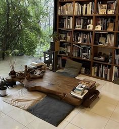 a living room filled with lots of books on top of a wooden table next to a window