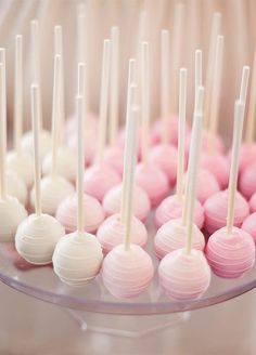 there are many pink and white candies on the plate with toothpicks in them