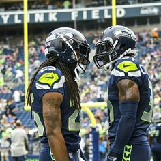 two football players standing next to each other in front of a stadium full of people