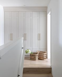 a hallway with white cabinets and baskets on the floor