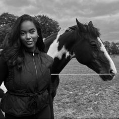 a black and white photo of a woman standing next to a brown and white horse