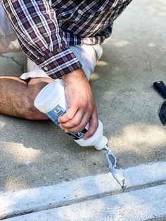 a man holding a bottle while kneeling down on the ground