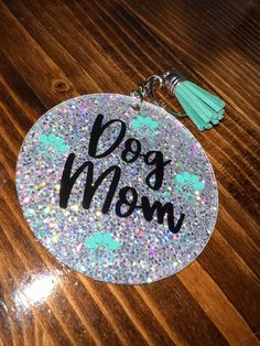 a dog mom keychain with glitter and tassels on top of it