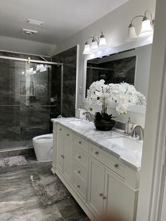 a bathroom with marble floors and white cabinets