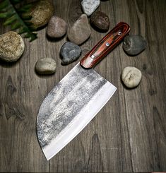 a large knife sitting on top of a wooden table next to rocks and stones,