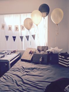 a bedroom with balloons and gifts on the bed