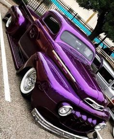 an old purple car parked in a parking lot