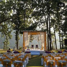 an outdoor wedding set up with yellow and white linens on the ground, surrounded by trees