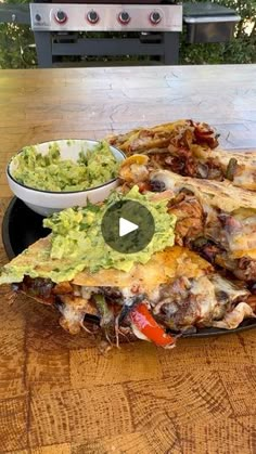 some tacos and guacamole are on a plate with a grill in the background