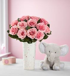 pink roses in a vase with an elephant toy