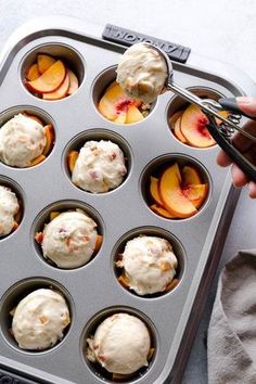 a person holding a spoon in a muffin tin filled with peaches and ice cream