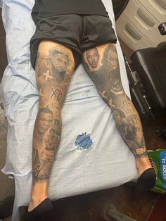 a man with tattoos on his legs laying in bed