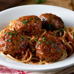 spaghetti with meatballs and parsley in a white bowl