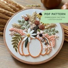 an embroidery pattern with flowers and leaves in the hoop on top of a wooden table