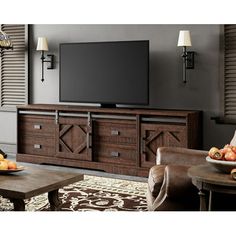 a large flat screen tv sitting on top of a wooden entertainment center in a living room