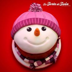 a frosted snowman with a pink hat and scarf on it's head