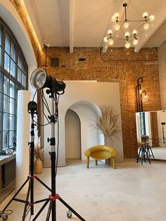 a photo studio with lights and chairs in front of a brick wall that has arched windows