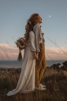 a bride and groom standing on top of a hill