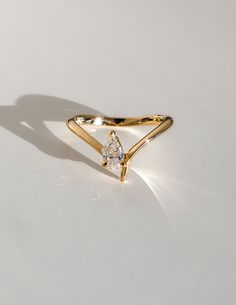 a yellow gold ring with a pear shaped diamond on the front and side, against a white background