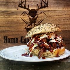 a sandwich with meat, cheese and onions on a plate next to a deer head