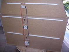 a cardboard box with wires attached to it and an electrical cord running through the middle